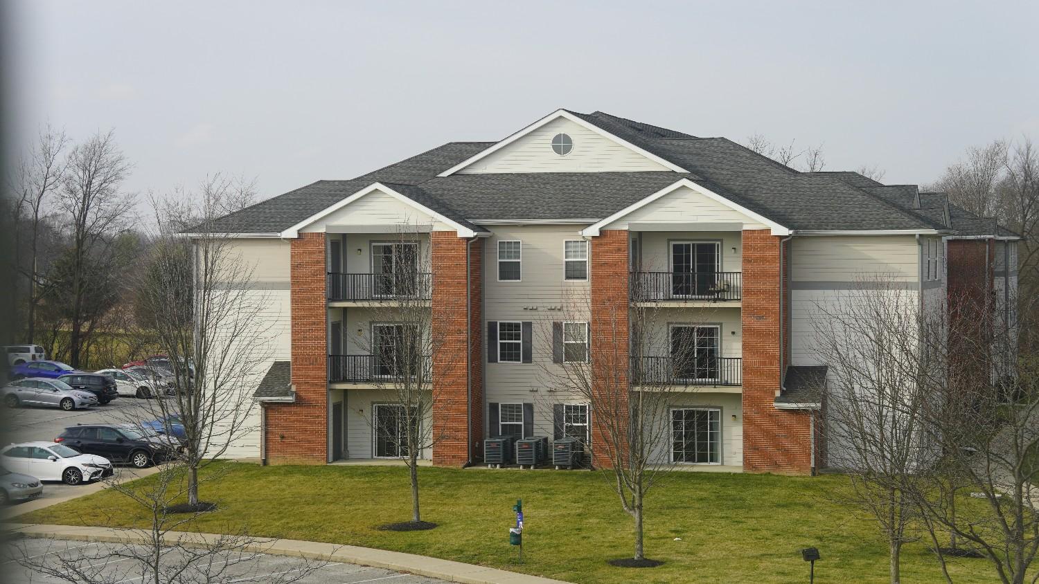 Multi-unit residential building with balconies, parking area, and shared grounds managed by a condo association