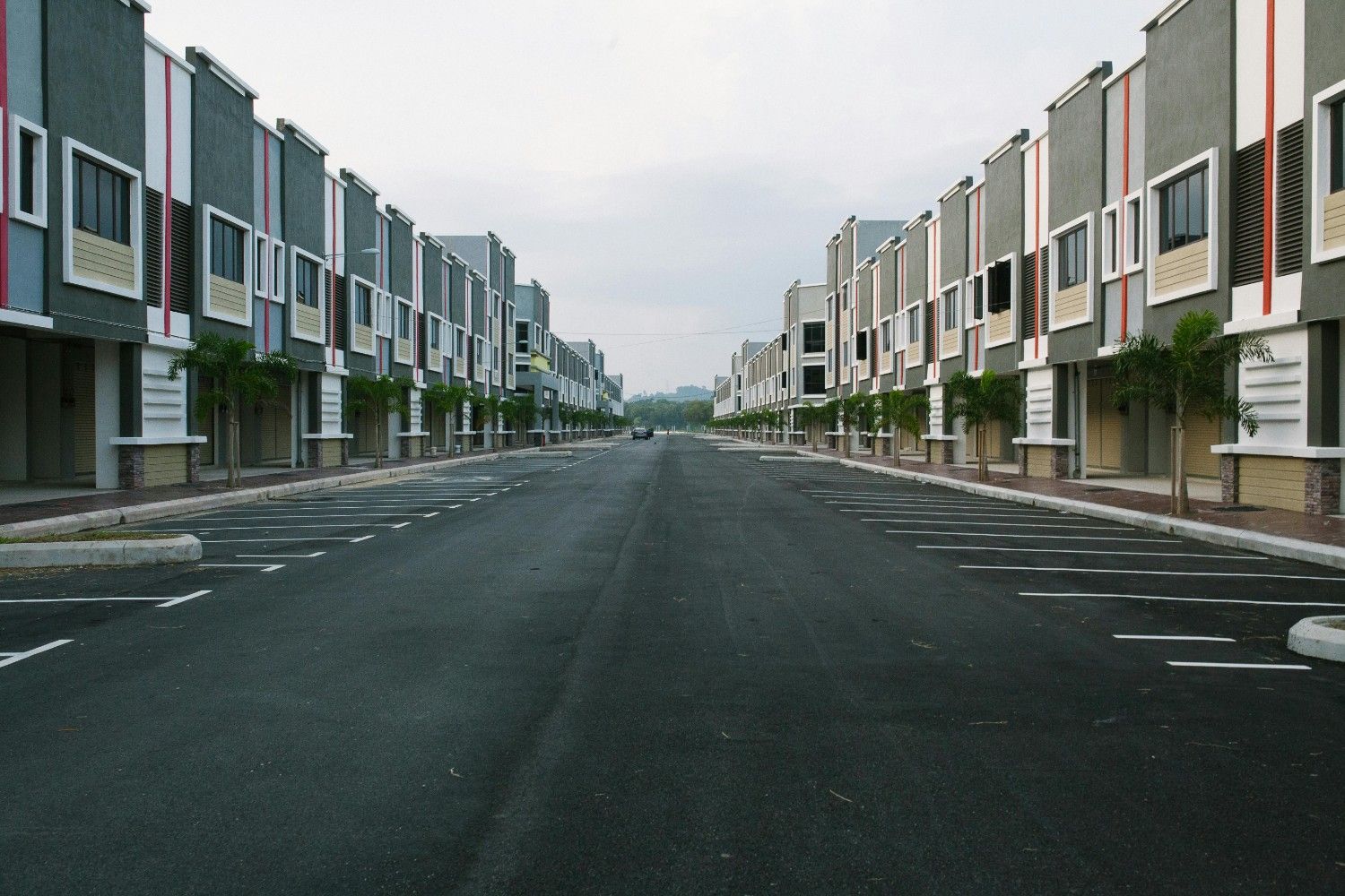 Symmetrical row of modern townhomes along a wide, newly paved street, showing organized streetscape design in a master-planned community.