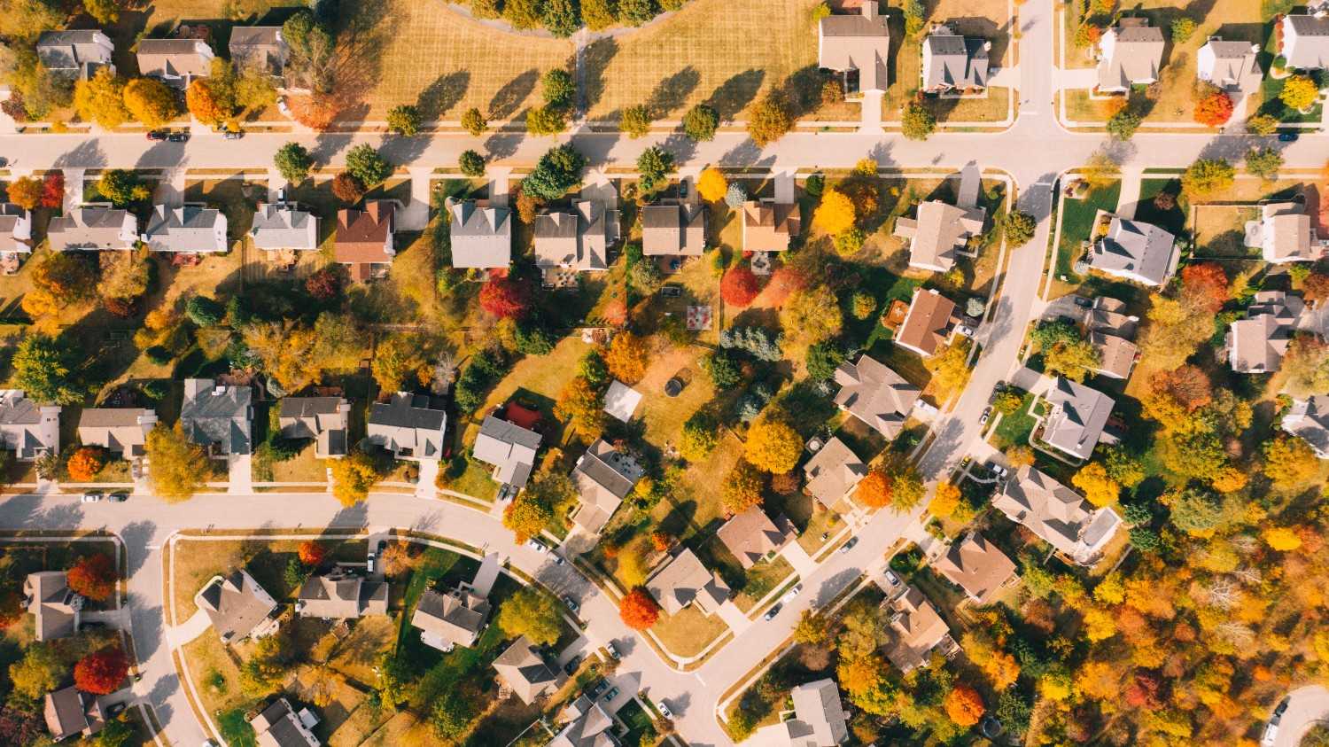 Aerial view of a suburban residential community with tree-lined streets, homes, and landscaped common areas.